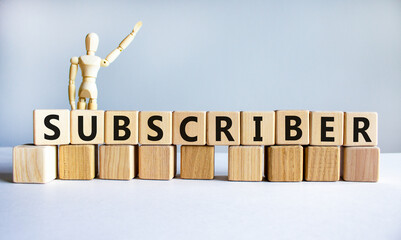 Subscriber symbol. The word Subscriber on wooden cubes. Wooden model of human. Businessman icon. Beautiful white background. Business and subscriber concept. Copy space.
