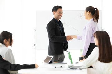 businesswoman and businessman  shaking hands together with partners for a job in conference room