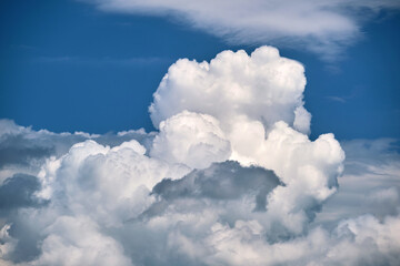 Bright landscape of white puffy cumulus clouds on blue clear sky.