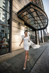 attractive woman walking in the city in a white dress 