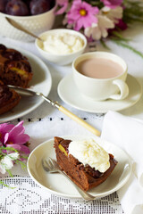 Chocolate plum cake with whipped cream, served with cocoa. Rustic style.