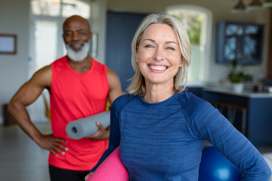 Portrait of happy senior diverse couple in exercise clothes practicing yoga, looking at camera