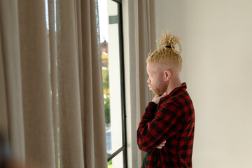 Thoughtful albino african american man with dreadlocks looking out the window