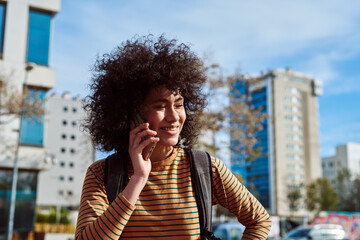 Fototapeta na wymiar Smiling young woman taking a phone call outdoors