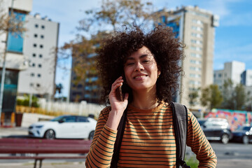 Smiling young woman taking a call in the city