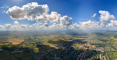 Aerial view from airplane window at high altitude of distant city covered with white puffy cumulus...