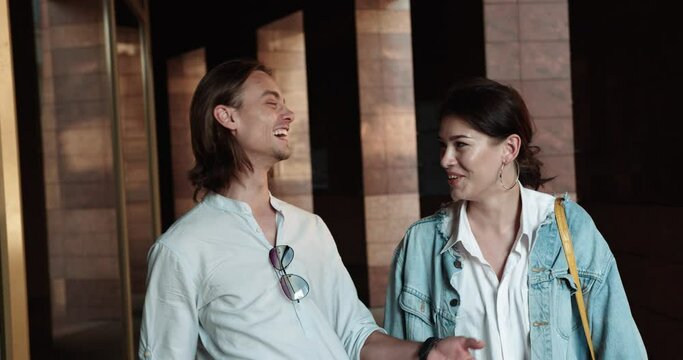 couple walking in the city. young man having fun telling a girl a funny story. couple guy and girl in normal clothes have a good mood. people laugh