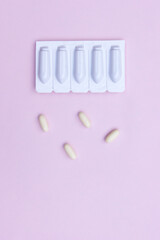 Gynecological medicines for women's health in form of suppository, capsules on pink background.