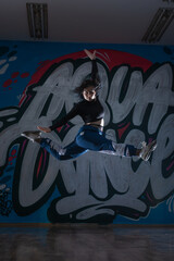 Female dancer in activewear squatting on the floor of modern dance studio and looking at you