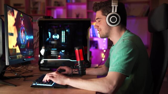 Side view of the professional guy gamer streaming and playing video game on computer