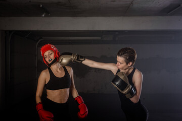 Two professional female boxers punching each other in aggressive garage boxing fight