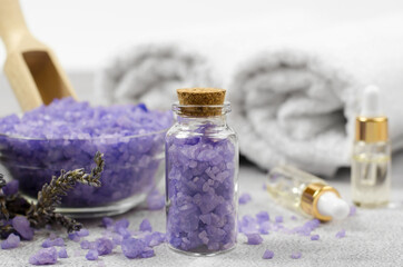 Fototapeta na wymiar Spa composition. Purple sea salt in a glass bottle against the background of essential oils and bath accessories.