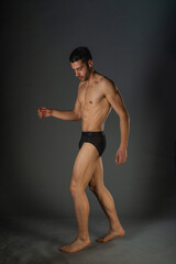 Naklejka premium Sexy man with a muscular body posing naked with black underpants inside a studio