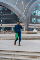 Handsome young man walking and talking on mobile phone in the city