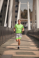 Male sportsman is running on the bridge