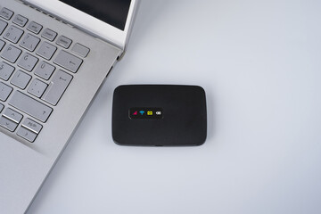 Pocket  wireless or internet. Mobile Wifi device near laptop or notebook on isolated white background.