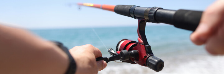 Man is fishing with line on seashore closeup