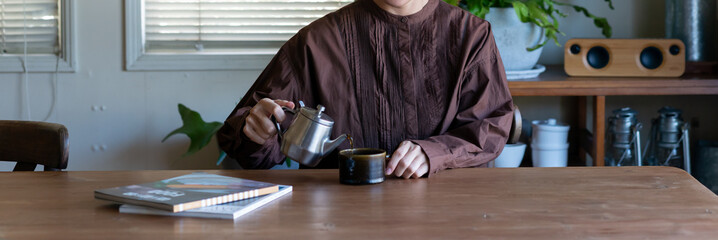 ティーポットからカップに紅茶・コーヒーを注ぐ女性