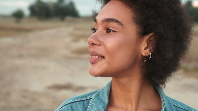 Close-up view of the happy african woman standing among the estuary and looking around