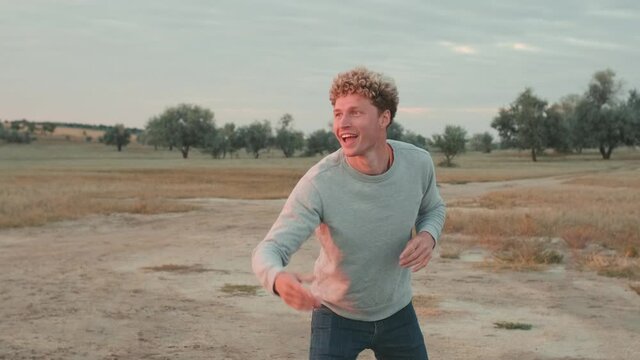 Laughing handsome man throwing frisbee while standing among the estuary 