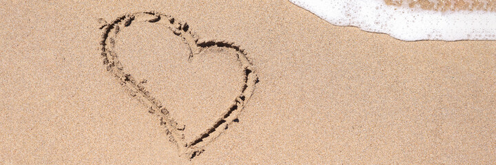 Drawn heart on wet sand next to sea closeup