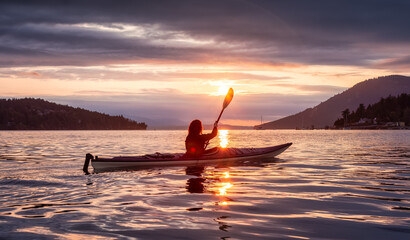 Adventurous Woman on Sea Kayaking in the Pacific Ocean. Summer Sunset Sky. Taken near Victoria, Vancouver Islands, British Columbia, Canada. Adventure Travel Concept