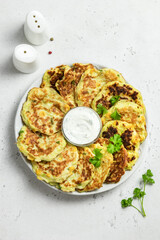 Vegan zucchini corn fritters with yogurt sauce. Space for text.