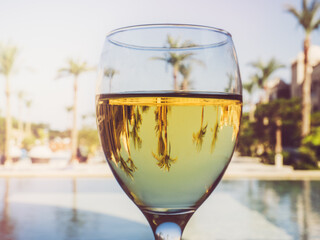 Beautiful glass of wine on the background of the pool. Side view, close-up. Concept of leisure and travel