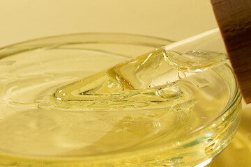 Closeup photography of the glass pipette with oil in the petri dish.