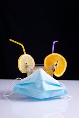 fruity coronavirus cocktail in protective mask concept on white table and black background