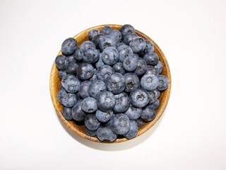 blueberries in a wooden bowl, top view on a white background