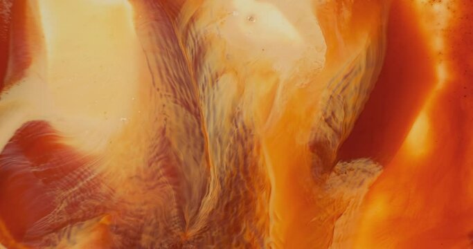 Red orange paints flowing abstract background. Red orange fiery river of liquid ink, close up. Colorful paints moving. Creative patterns of solar energy. 4K footage. Warm yellow liquid in motion