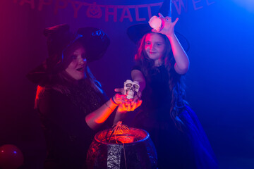Two halloween witches making a potion and conjure in halloween night. Magic, holidays and mystic concept.