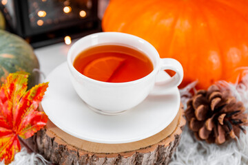  A cup of tea with lemon, autumn leaves and pumpkin close up. The concept of a cozy autumn at home.