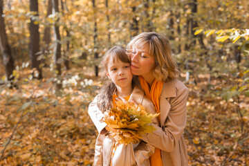 Beautiful lifestyle autumn photo mother and child walks evening in the park, warm sunlight.