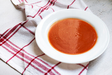 Cold tasty appetizing summer tomato soup. Bowl of traditional spanish soup puree gazpacho on light marble background. Copy space for text or design. Top view or flat lay