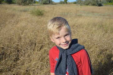Naklejka na ściany i meble The face of a satisfied child walking along the autumn steppe and puts his sunshine. 