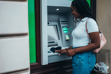 Fototapeta na wymiar African american woman using credit card and atm machine