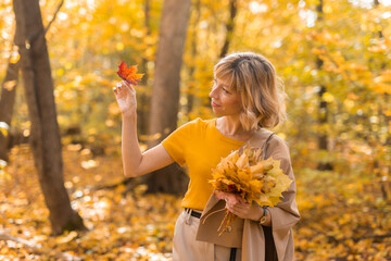 Portrait of beautiful young woman walking outdoors in autumn nature. Fall season and stylish girl concept.