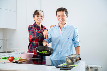 pareja joven sonriente cocinan verduras como pimientos verdes, tomate, jitomate y calabacin, con...