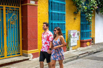 Beautiful tourist couple walking in the colorful streets of Cartagena de Indias, Colombia - obrazy, fototapety, plakaty