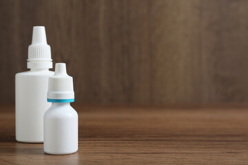 Bottles of nasal sprays on wooden table. Space for text