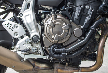 Titanium color motorcycle engine, black gear cooling line. brown muffler