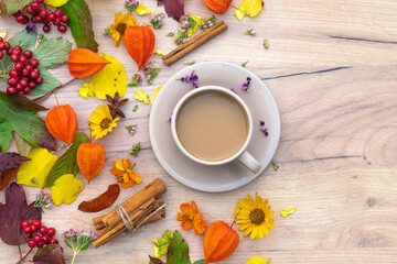autumn composition cup of coffee on a table with flowers and leaves, top view, background picture

