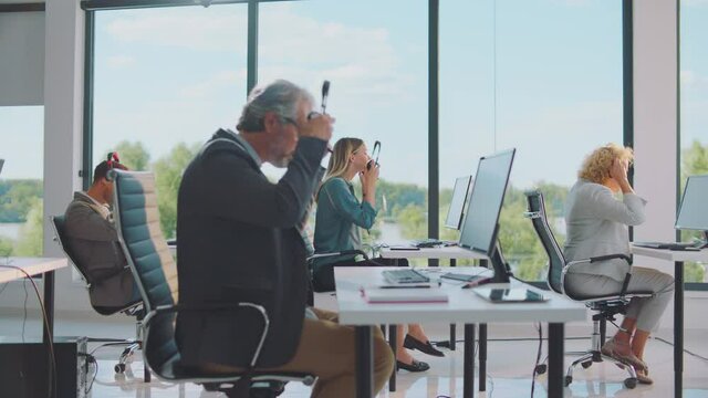 All people in office putting headset on their heads at same time. Start of online course. Modern open space office interior.