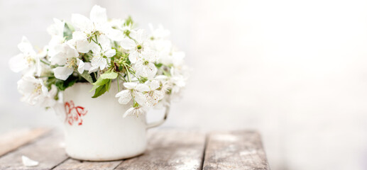 Still life with cup and bouquet of branches with apple blossoms. White petals of flowering trees that fell on concrete