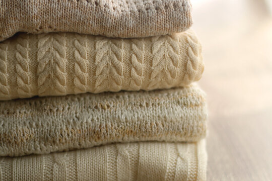 Pile of beige sweaters. Selective focus.