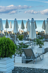 wooden ground on a pebble beach with sun loungers and umbrellas on the Black Sea coast in the resort town of Sochi, Russia