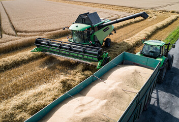 Getreideernte - Luftbild, Mähdrescher läßt Korn auf einen Transportanhänger ablaufen.