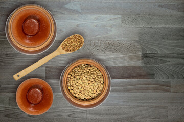 ceramic bowls with healthy grains and wooden spoons on textured wooden surface